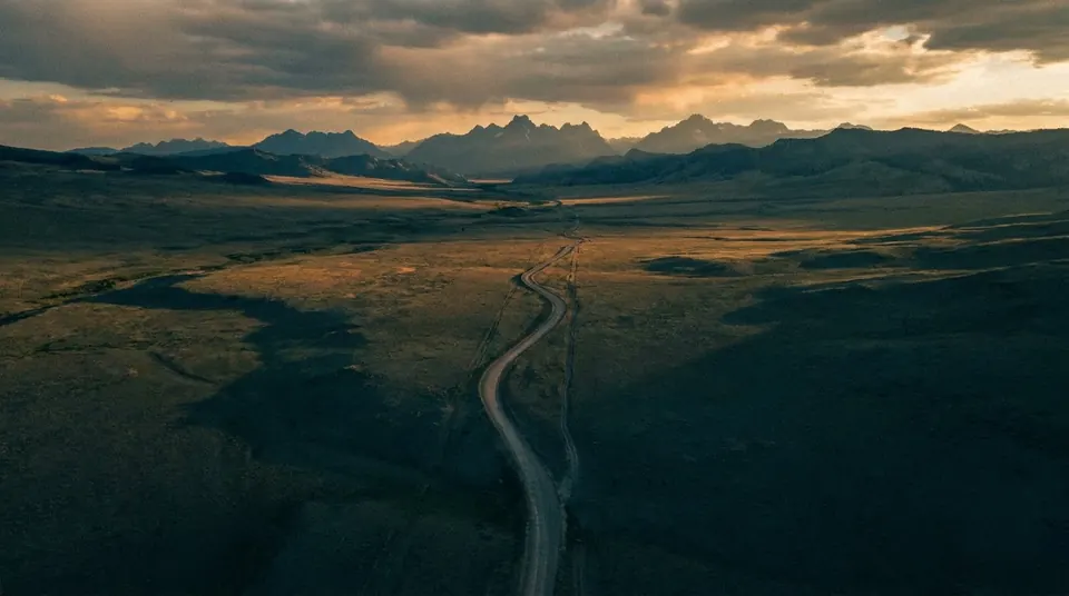Empty plains with a lonely road and distant mountains at dusk